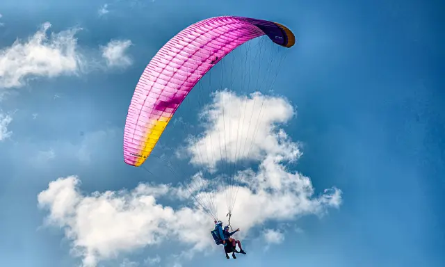 Tandem paraglider over green ridges