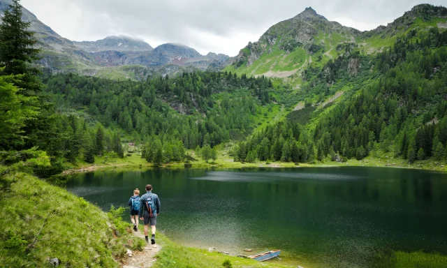 Hikers on a trail beside an alpine lake